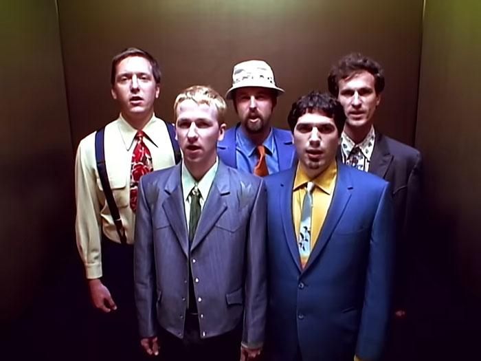 Five men wearing colorful suits and ties standing closely together, representing cool facts about the world.