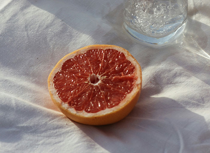 Half of a grapefruit on a white cloth next to a glass of sparkling water, reflecting cool facts about the world.