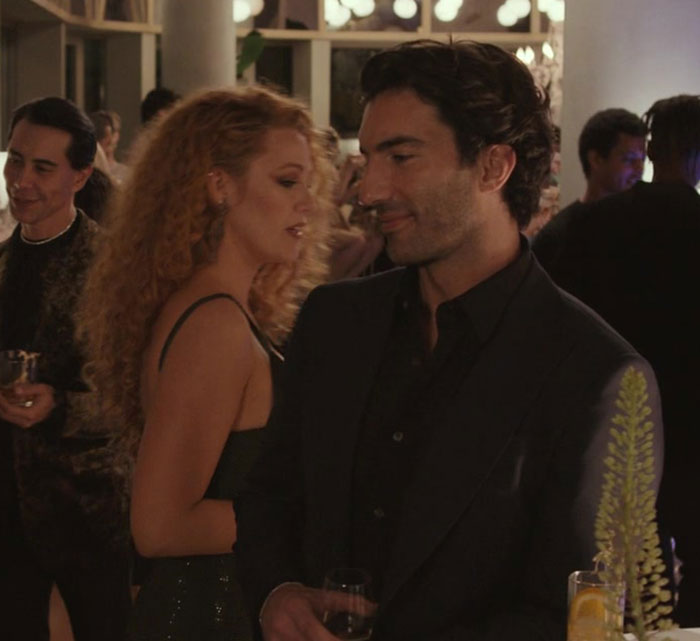 Blake Lively at a social event, dressed elegantly, engaging in conversation with attendees in a dimly lit room. - 11