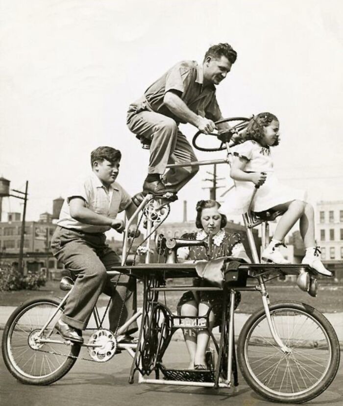 Vintage historical photograph of a multi-level bicycle with four people engaging in unique teamwork outdoors.