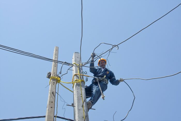 Electrician working on power lines on a pole, illustrating high-paying jobs that can help make 6 figures.