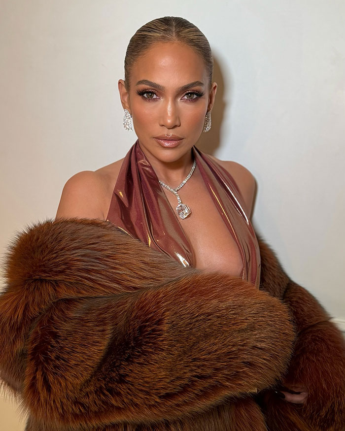 Jennifer Lopez wearing glamorous fur coat and jewelry, facing camera with confident expression in stylish look.
