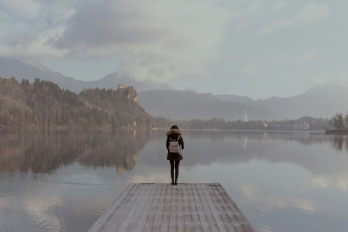 Person standing alone on a dock overlooking a calm lake at dawn, reflecting the peacefulness of night shift workers. - 17