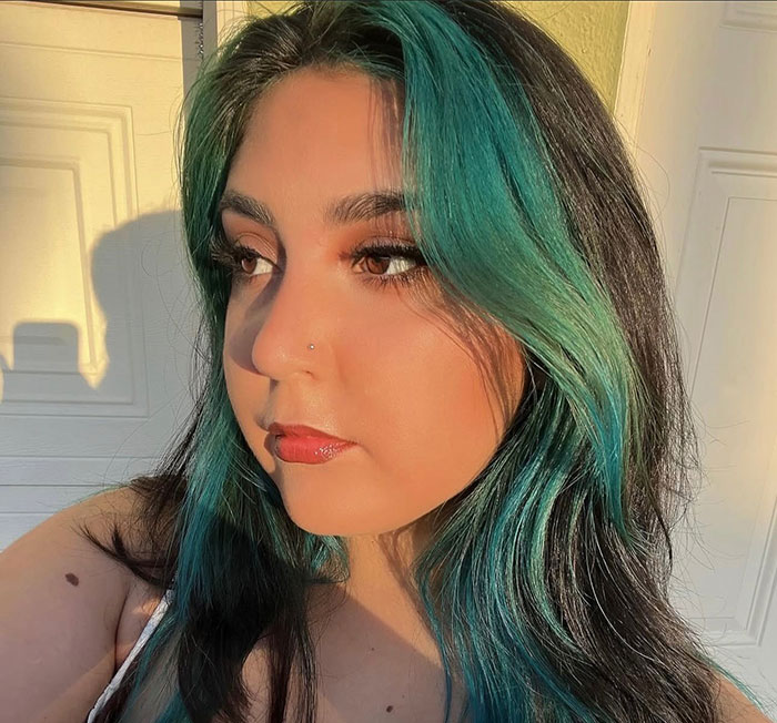 Young woman with teal and black hair in warm sunlight, related to 7-Eleven worker passes away after manager incident.
