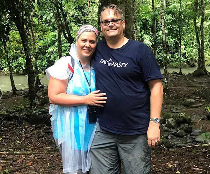 White foster dad and woman standing in forest near river, related to trafficking accusations by United Airlines crew.
