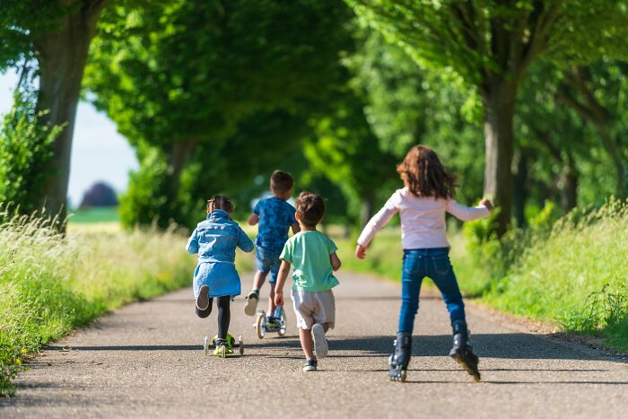 Four children riding scooters and rollerblades on a tree-lined path, enjoying the benefits of outdoor activity. - 10