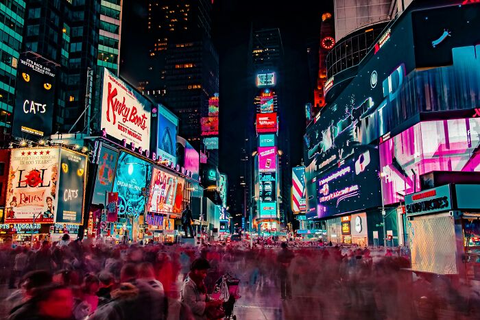 Crowded Times Square at night with bright digital billboards and blurred travelers showcasing surprising things about the U.S.