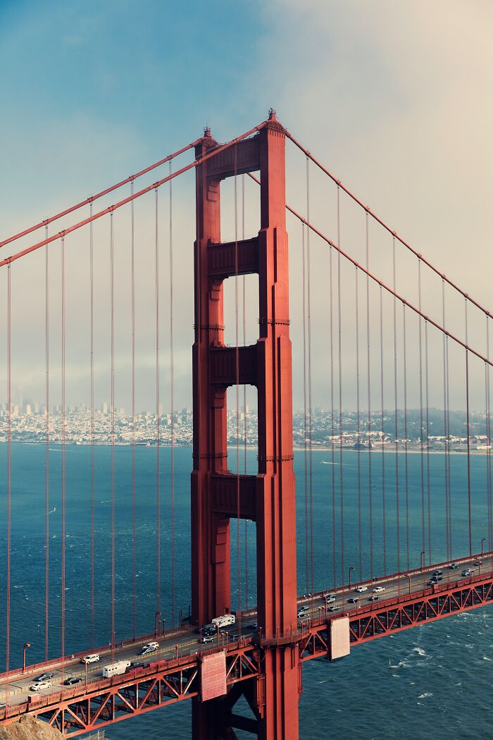 Golden Gate Bridge tower with traffic below over water, symbolizing infrastructure on the brink of collapse issues. - 21