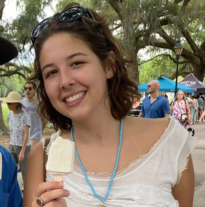 Young woman smiling outdoors at a park event, reflecting on the fear young flood victim must have felt.