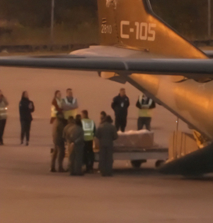 Rescue team at an airport near a plane preparing equipment related to hiker abandoned inside active volcano incident.