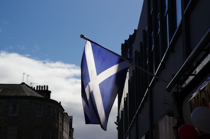 Scottish flag waving against a blue sky on a building, symbolizing bravery that changed the course of history. - 16