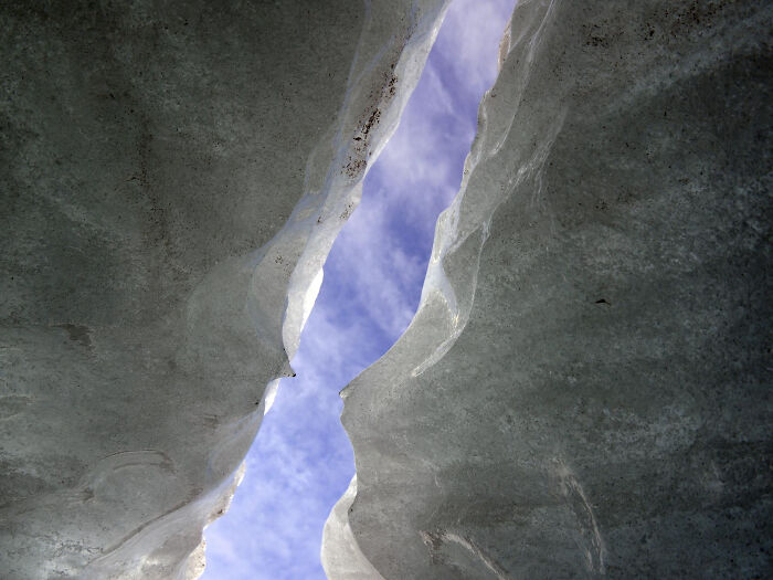 View looking up through a narrow ice crevice with a blue sky, symbolizing people's bravery changing the course of history. - 4