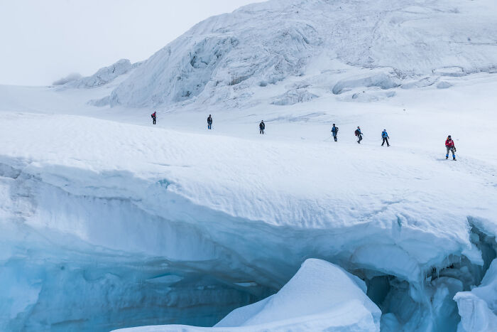 Group of explorers demonstrating bravery while trekking across a vast icy glacier in challenging conditions. - 22