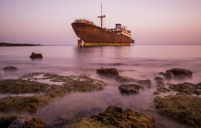 Rusty abandoned shipwreck near rocky shore at sunset, symbolizing bravery that changed the course of history. - 30
