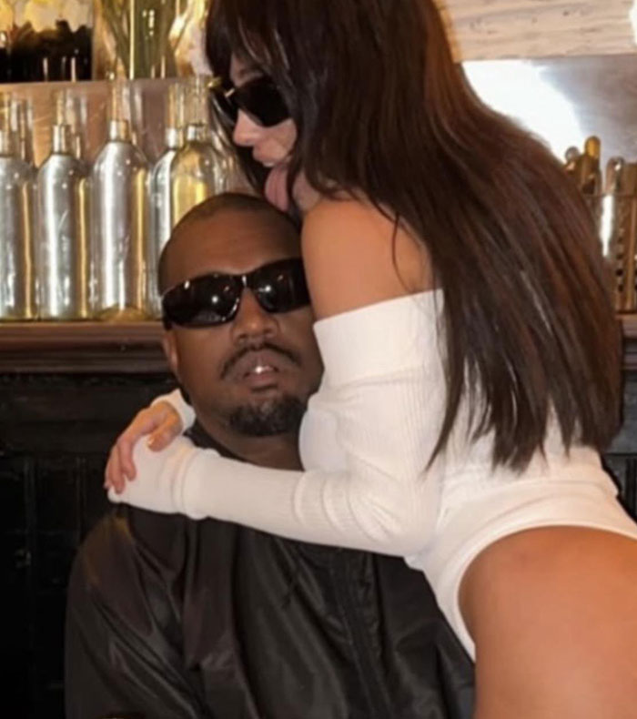 Kanye West wearing sunglasses with Bianca Censori in a white sheer nightie posing closely indoors. Kanye West wearing sunglasses with Bianca Censori in a white sheer nightie posing closely indoors.