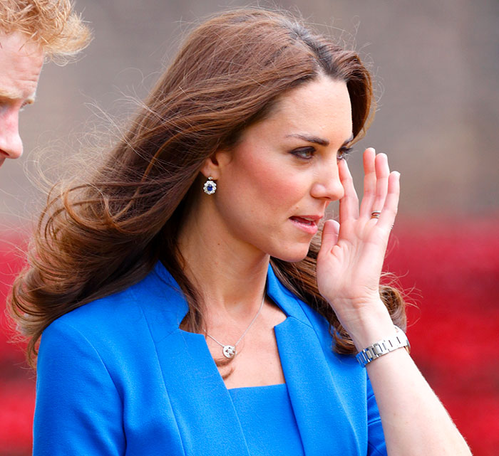 Kate Middleton in a blue outfit appearing thoughtful and concerned during a public appearance related to cancer awareness.