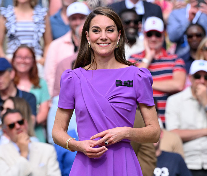 Kate Middleton smiling in a purple dress at a public event, capturing a candid moment highlighting cancer confession.
