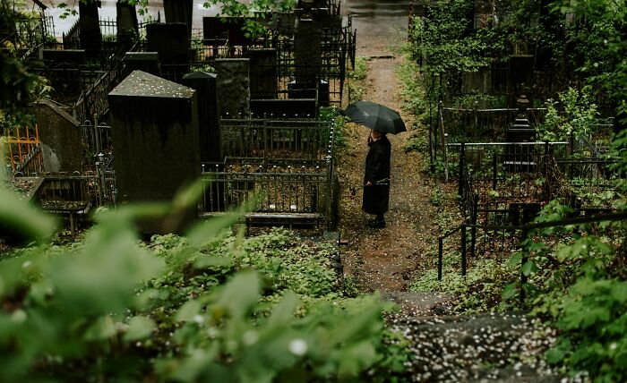 Person holding an umbrella walking through an old cemetery, representing overlooked jobs that make 6 figures.