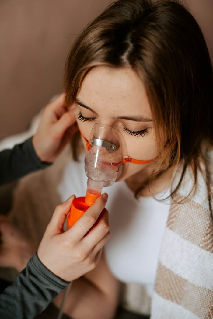 Young woman using an oxygen mask with someone helping, illustrating the impact of toxic best friends on health and well-being. - 1