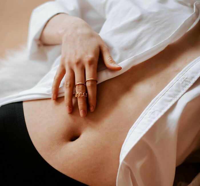 Close-up of a person’s hand with rings resting on their exposed stomach, representing rare phobias and body awareness concepts. - 21