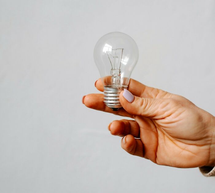 Hand holding a clear light bulb against a plain background, representing surprising items found by medical professionals.