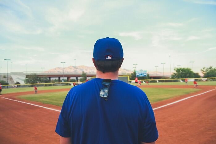 Coach in a blue shirt watching a school baseball game, capturing a moment of a messed up school incident. - 9