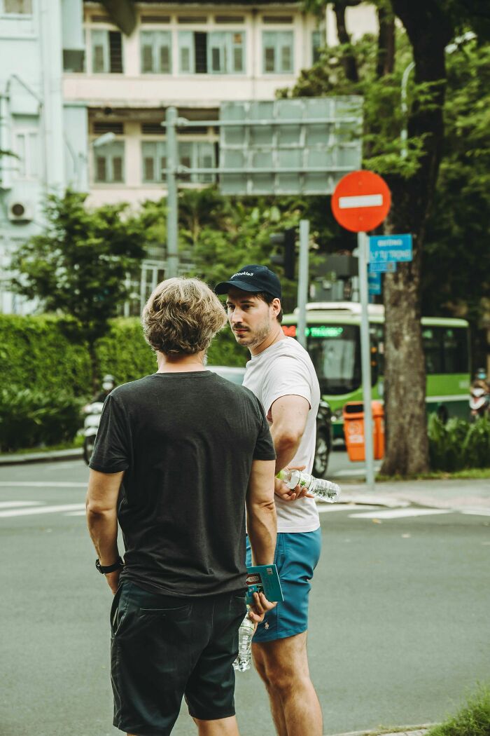 Two men standing outdoors having a conversation, illustrating things that are perfectly normal to men but seem bizarre to women.