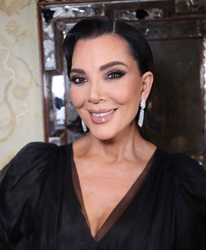 Kris Jenner posing in elegant black outfit and diamond earrings amid skeleton Barbie leg Photoshop controversy.