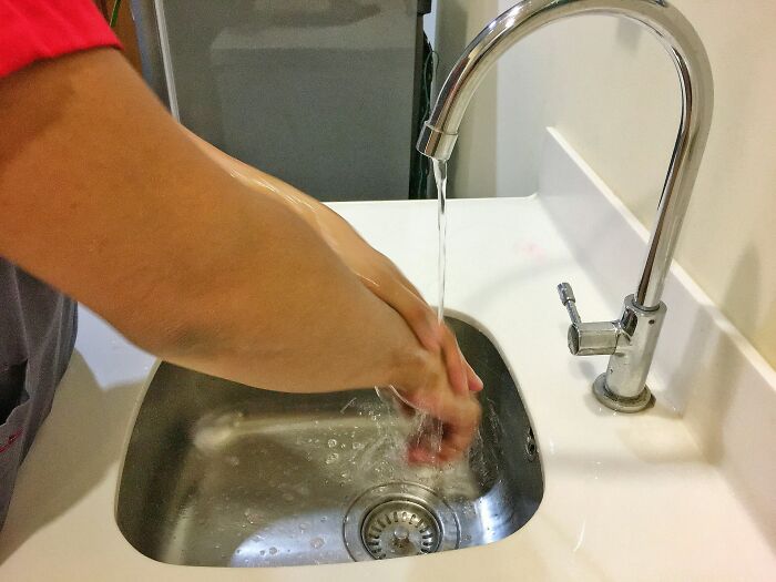 Person washing hands under running water at a modern sink, illustrating calm and mindful communication skills.
