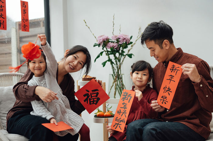 Family celebrating with red decorations and showing good-luck charms, featuring a ladybug as a symbol of fortune. - 4