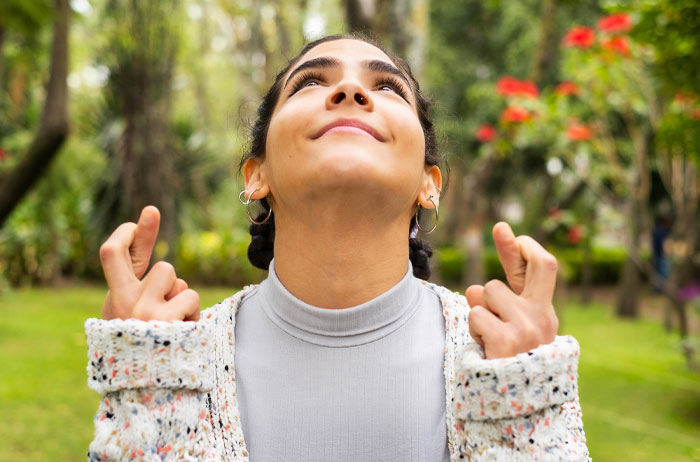 Young woman outdoors crossing fingers, hoping for good luck inspired by the ladybug as a universal charm. - 6