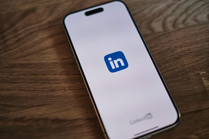 Smartphone displaying LinkedIn logo on screen, representing a person pretending to be employed and landing a better job. Smartphone displaying LinkedIn logo on screen, representing a person pretending to be employed and landing a better job.