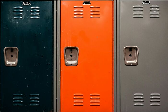 Close-up of three school lockers in dark green, orange, and gray, representing messed up school incidents. - 31