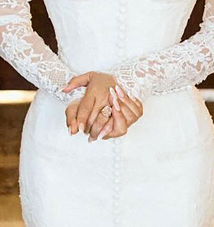 Close-up of Lauren Sanchez in a lace wedding dress with hands clasped, highlighting editing blunders in Photoshopped wedding pictures.