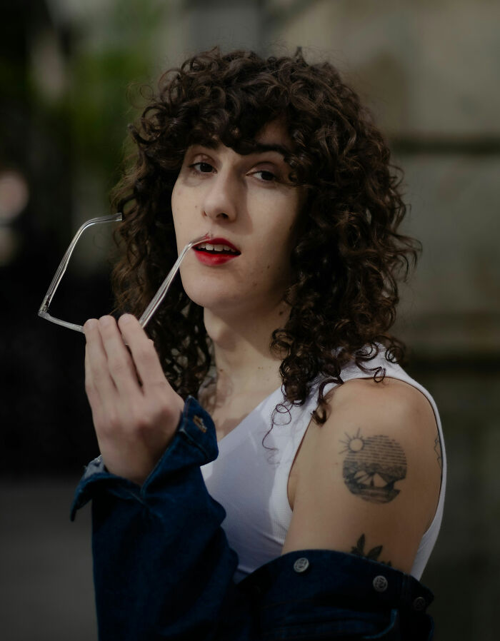 Person with curly hair and red lipstick holding glasses, displaying confidence and subtle signs of toxic femininity behavior. - 30