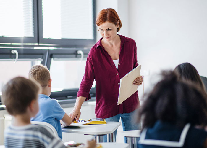Teacher in a classroom interacting with students, highlighting concerns about the US literacy crisis and education challenges.