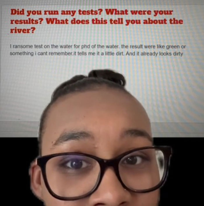 Close-up of a person wearing glasses with text about literacy crisis concerns displayed on a screen behind them.