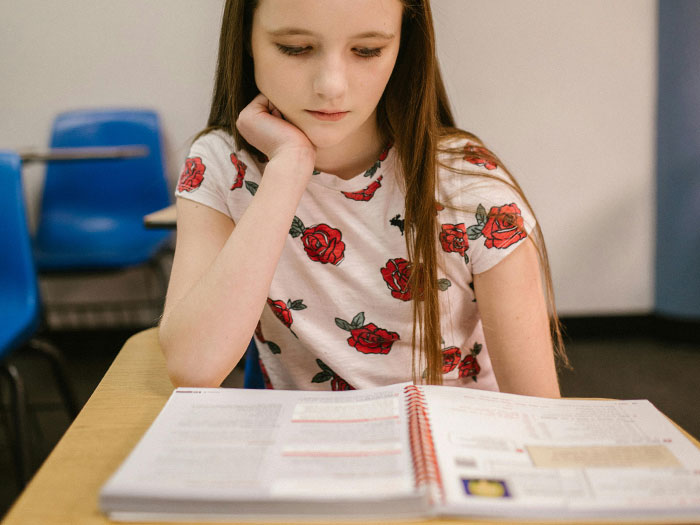 Young student reading a textbook in a classroom setting highlighting the US literacy crisis concern among teachers.