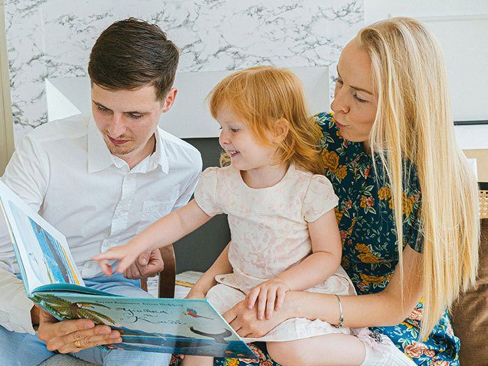Parents and child reading a book together, highlighting US teachers' concerns about the growing literacy crisis.