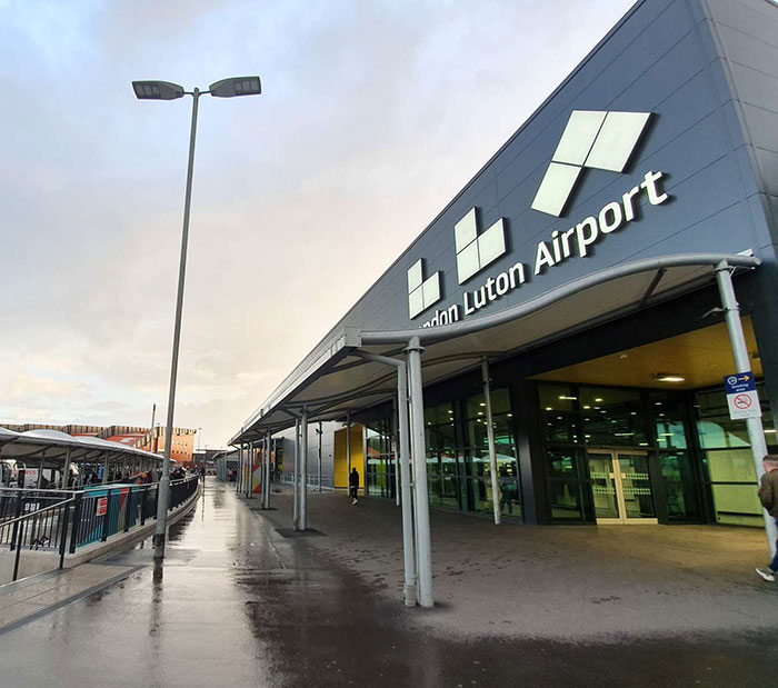 London Luton Airport exterior with wet pavement, relating to man threatening to explode plane mid-flight incident.