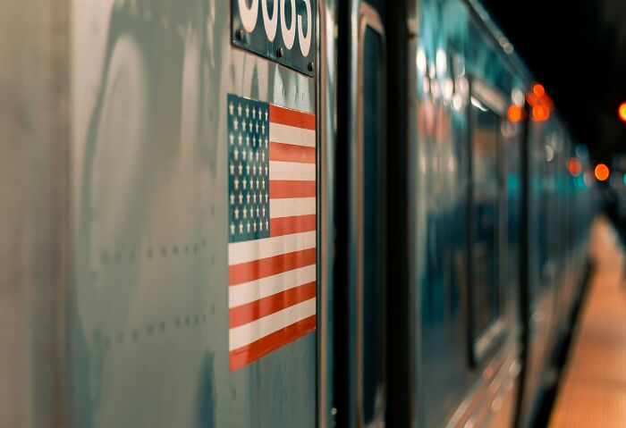 Close-up of a U.S. flag decal on the side of a train at night, highlighting travelers surprising things about the U.S.