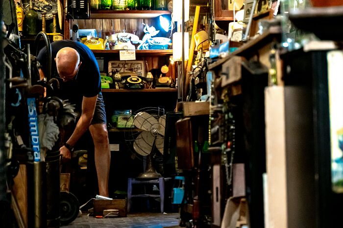 Man in a cluttered antique shop surrounded by vintage items, illustrating stories from married people stuck with spouses.