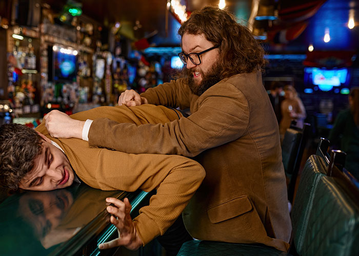 Man using quick thinking to restrain another in a tense crime or dangerous situation at a dimly lit bar.