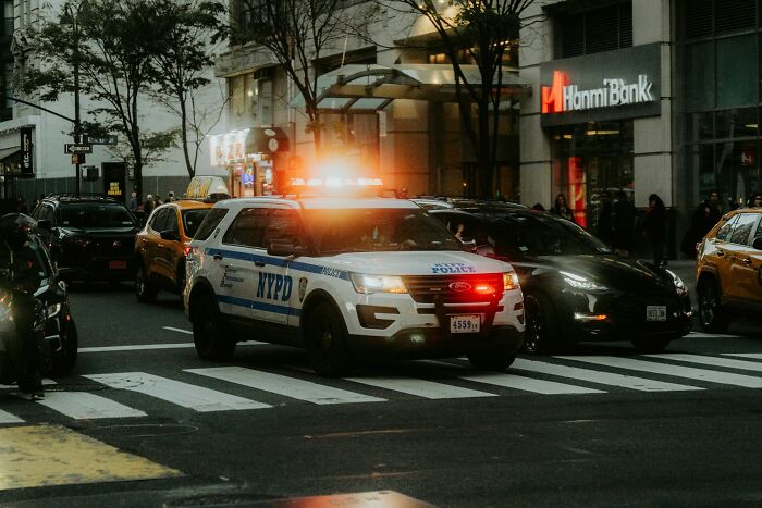 NYPD police car with lights flashing on a city street, relating to people who ran away from home stories. - 15
