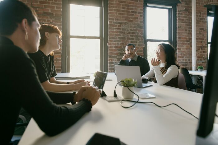 Group of diverse students discussing outrageous student names while using laptops in a bright modern classroom setting