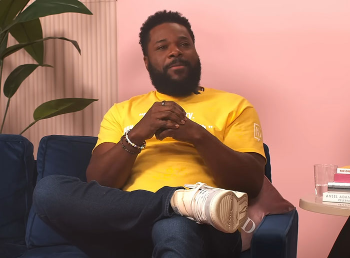 Malcolm-Jamal Warner in yellow shirt sitting on sofa during one of his final public appearances amid mourning - 4