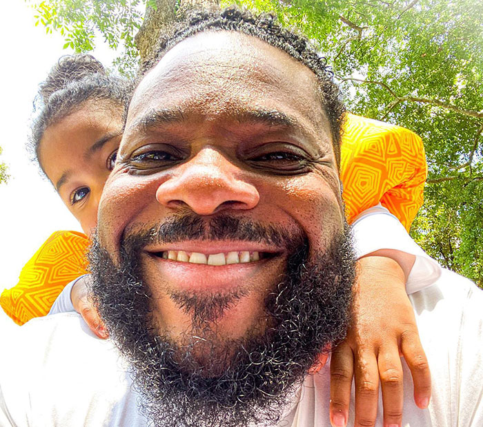 Malcolm-Jamal Warner smiling outdoors with a child on his back during one of his final public appearances. - 8