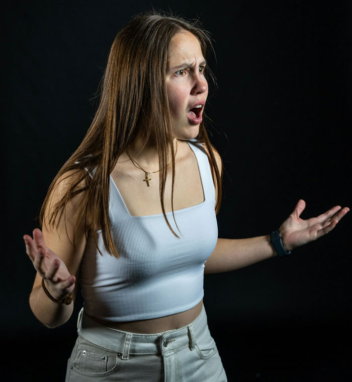 Young woman in white top expressing shock and anger, depicting tension related to man threatening to cut off his mother. - 10
