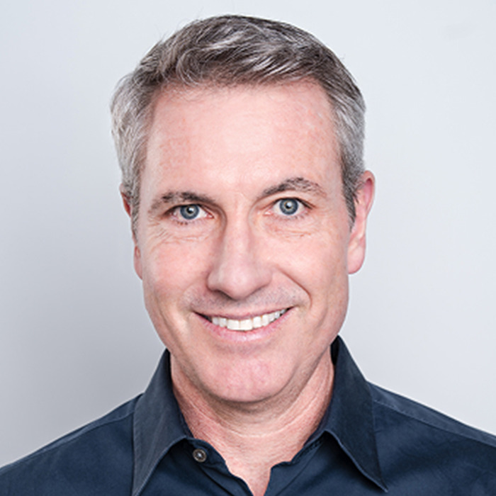 Middle-aged man with gray hair and blue eyes smiling, representing sociopath CEO discussed in violent school story.