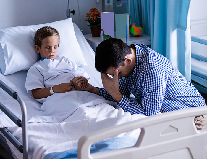 Father holding hand of sick child in hospital bed, showing concern and sadness during a difficult moment. - 1